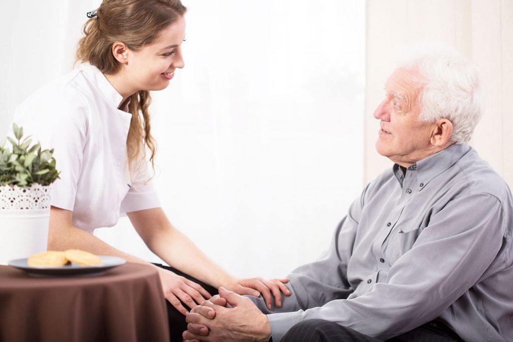 A woman is holding the hand of an older man.